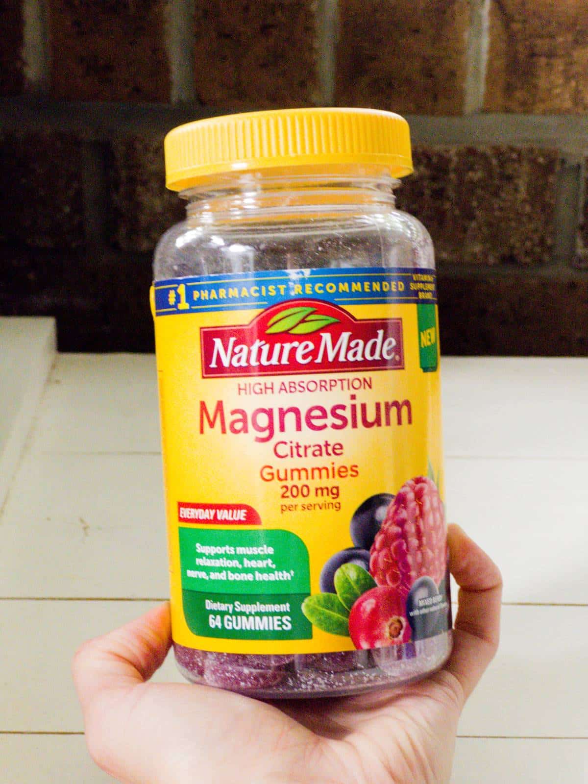 The blog author's hand holding a bottle of Magnesium Citrate Gummies supplements.