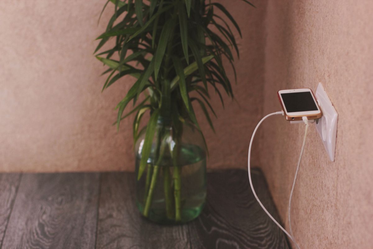 A Smartphone charging outside the bedroom on a wall charger.