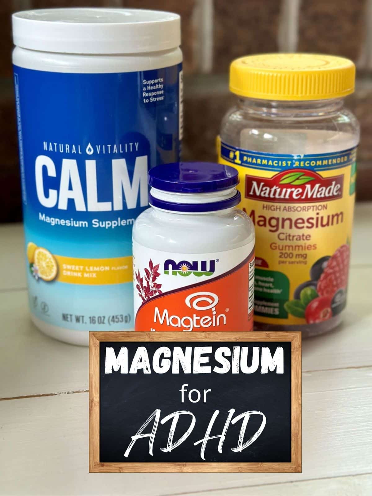 A bottle of NOW Magnesium L-Threonate, a bottle of Magnesium Citrate Gummies, and a Container of Magnesium Calm Powder Supplement on a table with the text overlay "Magnesium for ADHD."