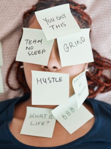 A woman overwhelmed by too many tasks with post it notes with things to do written on each note.