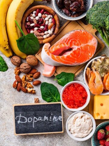 An overhead shot of fish, bananas, nuts, and other healthy foods that increase dopamine naturally with the text "dopamine."