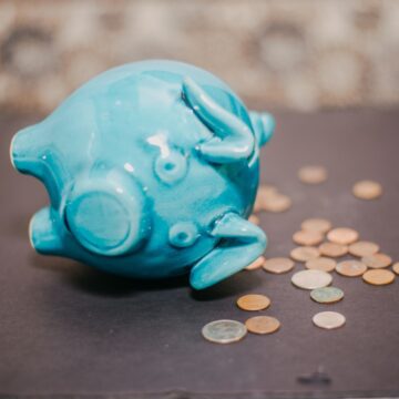 A piggy bank knocked over with coins coming out.