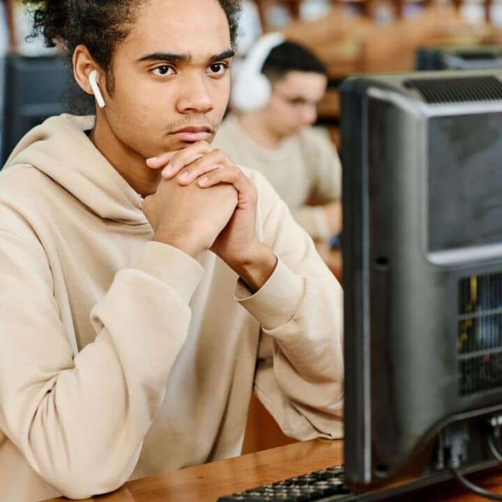 A young man thinking in front of a computer.